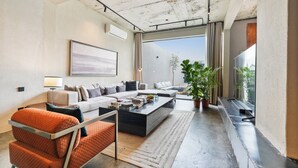 Ein modernes Wohnzimmer mit einer Sofagarnitur, einem Couchtisch und einem großen Fenster mit Blick ins Freie.