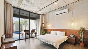Ein modernes Hotelzimmer mit einem großen Bett, einem kleinen Schreibtisch, einem Stuhl und einer Topfpflanze.