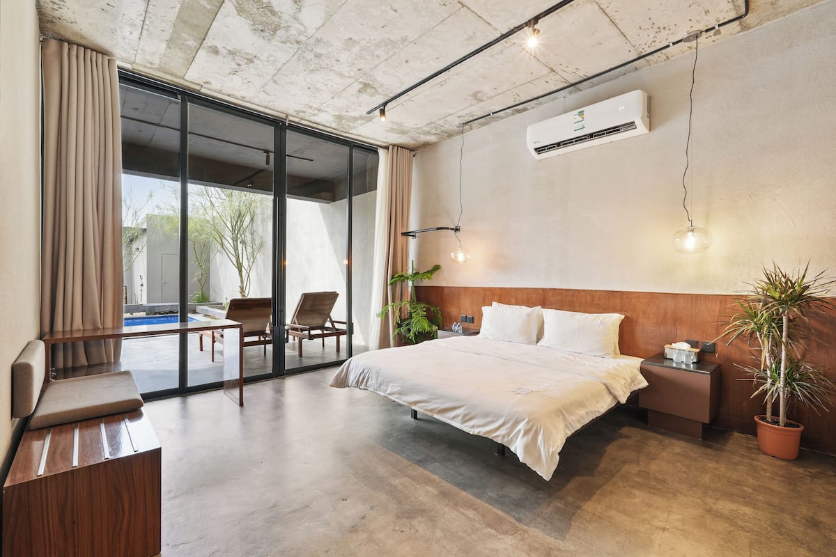Una habitación de hotel moderna con una cama grande, un escritorio pequeño, una silla y una planta en maceta.