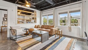 Ein modernes Wohnzimmer mit einer Couch, einem Couchtisch und einem großen Fenster mit Blick auf Palmen.