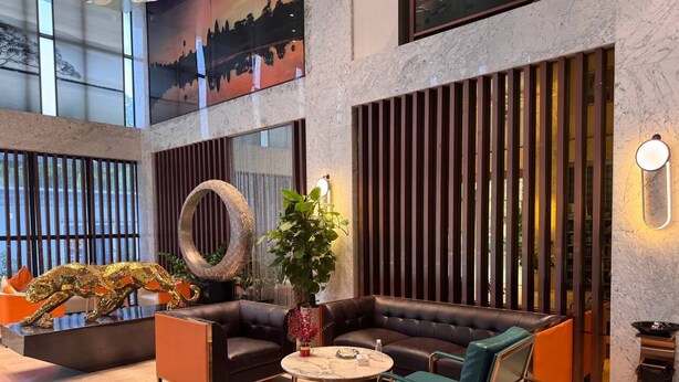 Un lobby moderno con un sofá modular, una mesa de centro redonda y una planta decorativa.