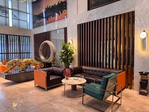 A modern lobby with a sectional sofa, a round coffee table, and a decorative plant.