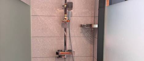 A modern shower with a handheld showerhead and a fixed overhead showerhead, mounted on a wall with a tiled floor.
