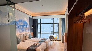 Una habitación de hotel moderna con dos camas, un ventanal grande y vistas a la ciudad.