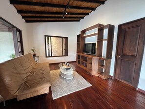 A living room with a sofa, a glass coffee table, a wooden entertainment unit, and a television. - Beautiful country (Rionegro)