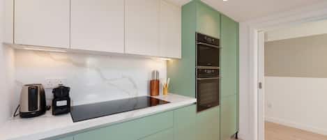 A modern kitchen with a white countertop, green cabinets, and a built-in oven.