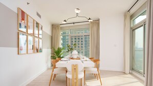 A modern dining area with a round table set for six, surrounded by wooden chairs.