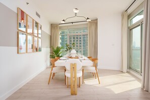 A modern dining area with a round table set for six, surrounded by wooden chairs.