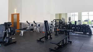 A gym with weightlifting equipment, benches, and dumbbells.