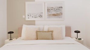 A bedroom with a bed, two bedside tables, and two wall-mounted lamps.