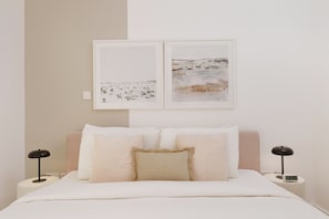 Un dormitorio con una cama, dos mesitas de noche y dos lámparas de pared.