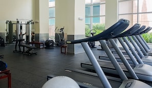 A gym with treadmills, weight machines, and a bench.