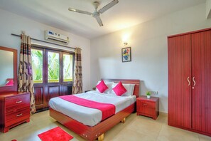 A bedroom with a bed, a wardrobe, a nightstand, a mirror, and a ceiling fan. - Ocean Dream Luxury Villa (Arpora)