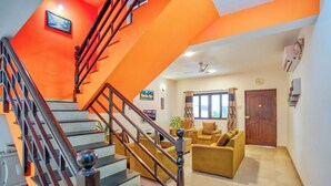 A staircase with a wooden handrail leading to a living area with a sofa and a window. - Ocean Dream Luxury Villa (Arpora)