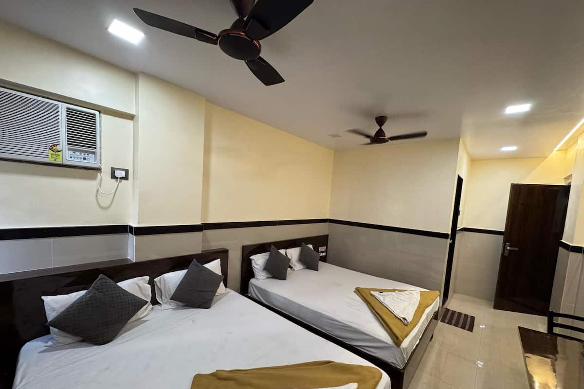 A hotel room with two beds, ceiling fans, a wall-mounted air conditioner, and a door leading to another room.