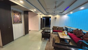 A modern living room with a sofa set, a coffee table, and a ceiling fan. - Hotel B K House (Noida)