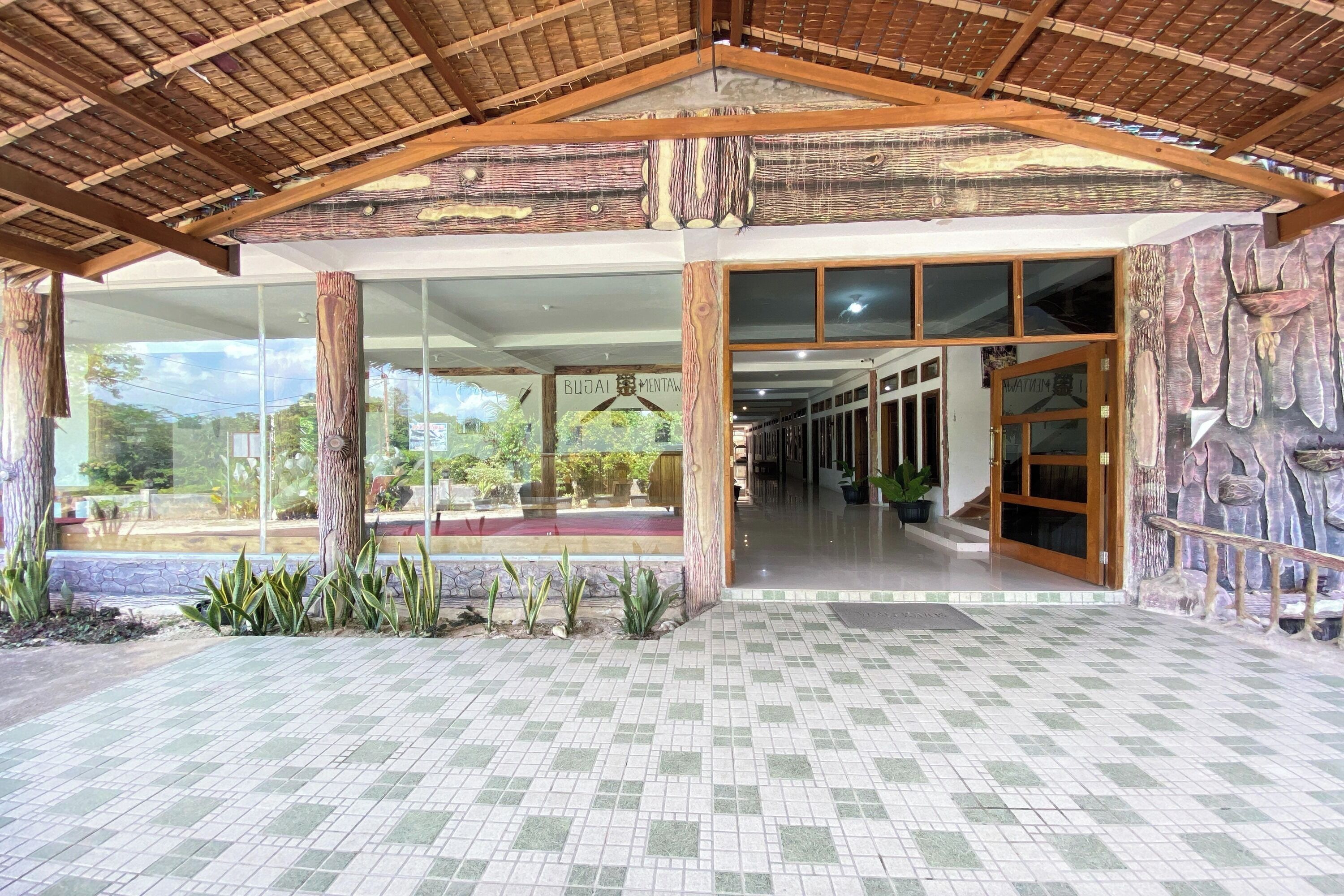 A building entrance with a tiled floor, wooden beams, and glass doors.