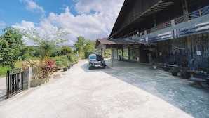 A paved driveway leading to a building with a thatched roof and a covered walkway.