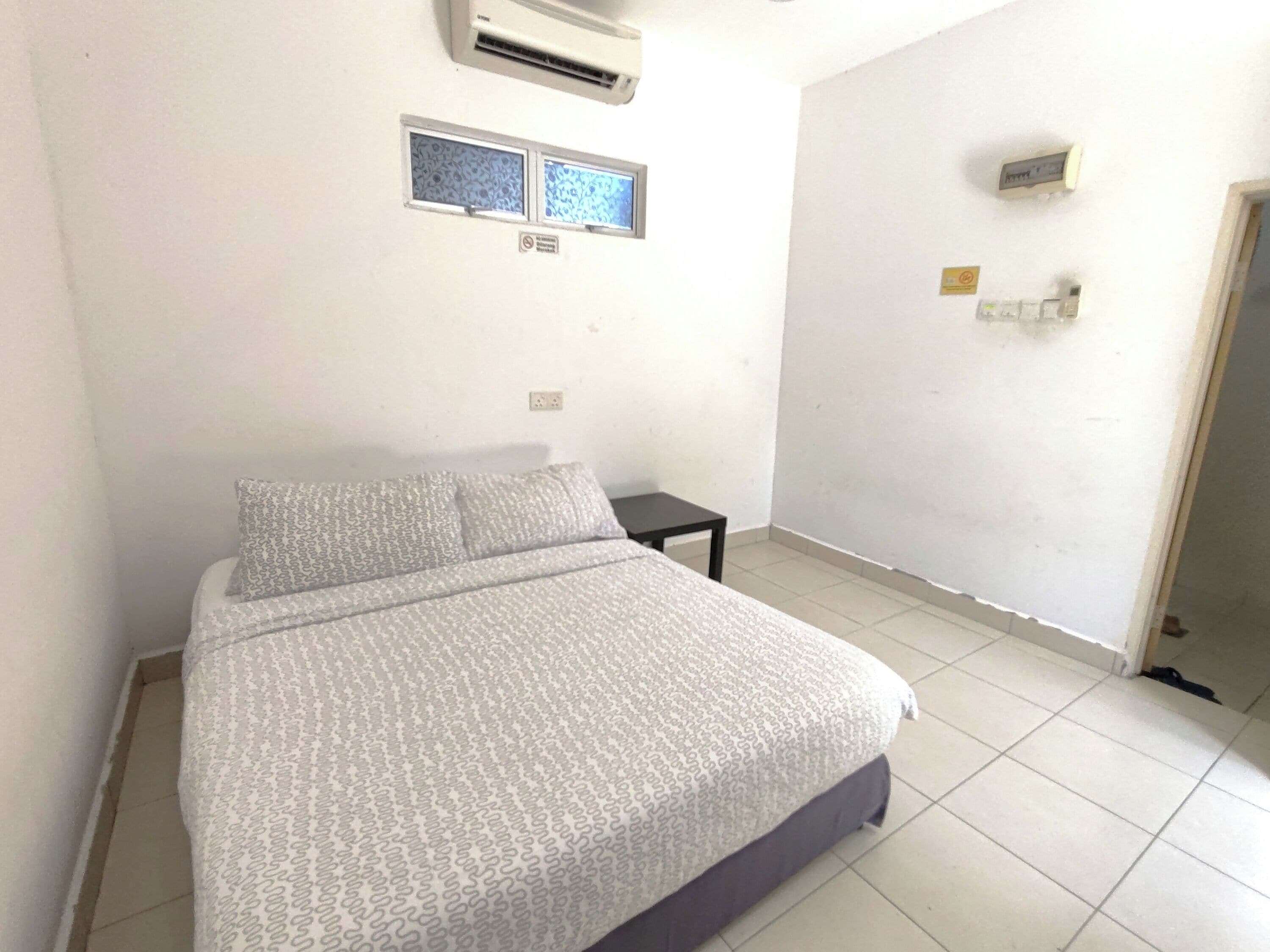 Een slaapkamer met een bed, een klein tafeltje, een airconditioning en een raam met uitzicht.