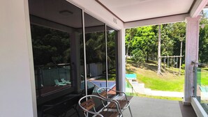 Ein Balkon mit Glastür, einem Tisch und zwei Metallstühlen.