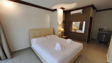 A hotel room with a large bed, a bedside table with a lamp, a mirror, and a wardrobe.