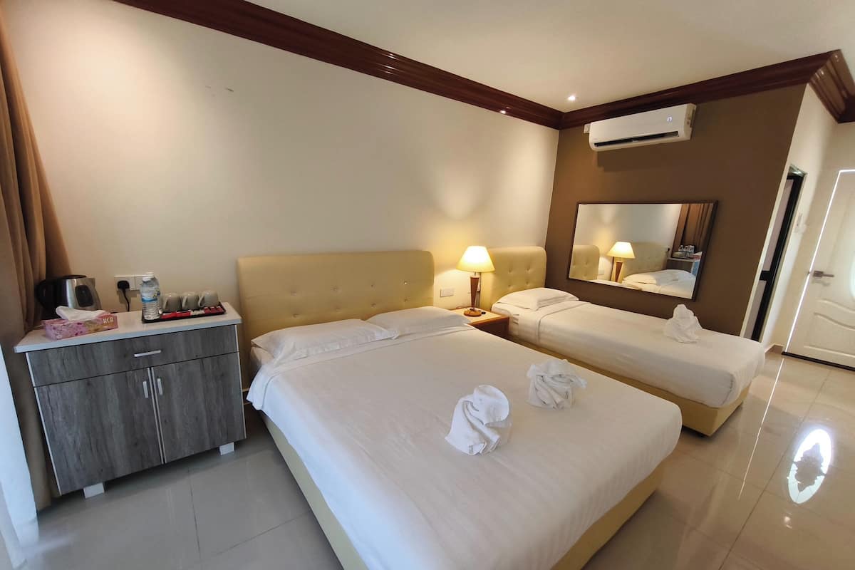 Ein Hotelzimmer mit zwei Betten, einem Holzkasten, einem Schreibtisch mit Lampe und einer Klimaanlage.