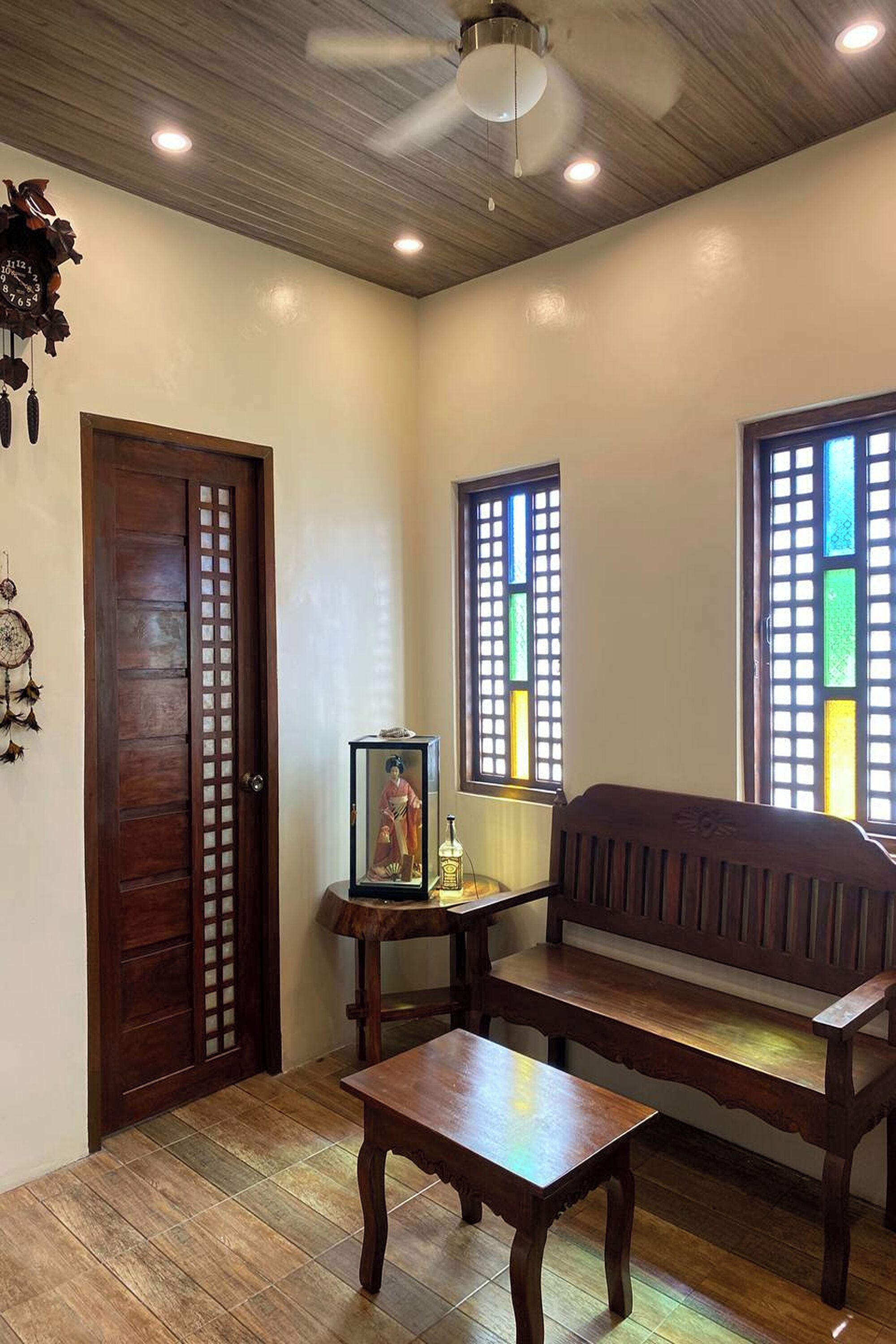 A traditional room with a wooden door, a bench, a small table, and a framed picture on a stand.
