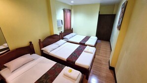 Une chambre d’hôtel avec deux lits simples, une tête de lit en bois, une petite table de chevet, un appareil de climatisation et une porte.