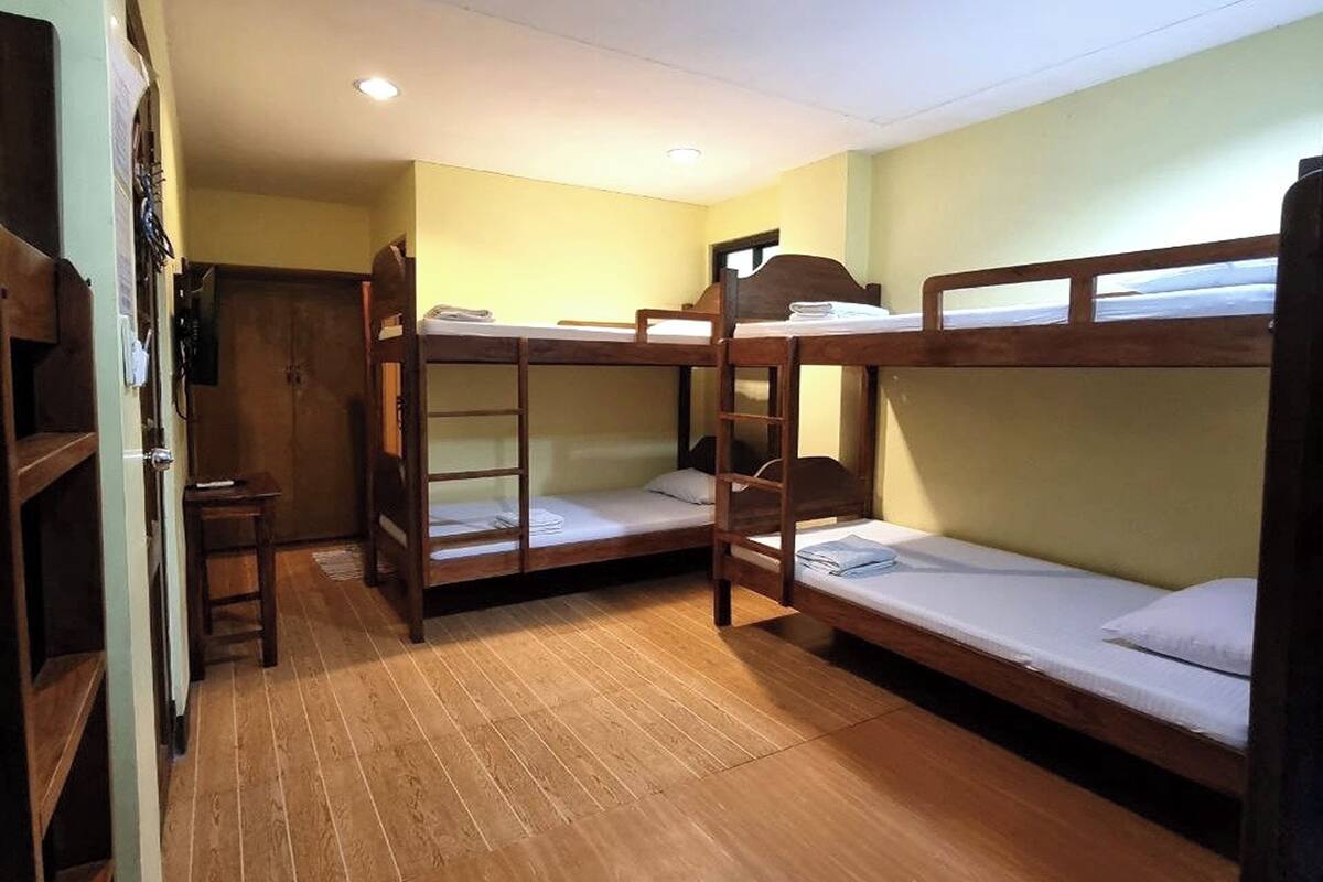 Une chambre de dortoir avec des lits superposés, un plancher en bois et un petit bureau.