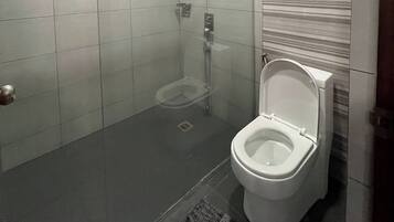 A bathroom with a toilet, a shower, and a tiled floor.