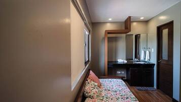 Un dormitorio con cama, mesita de noche, espejo, cómoda y puerta.