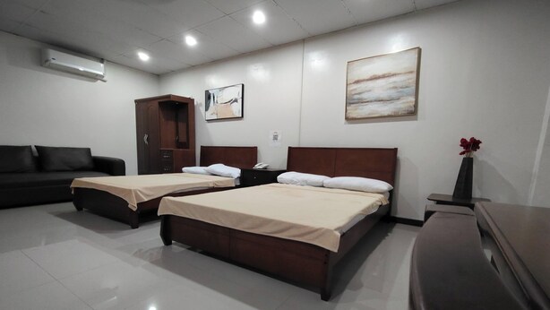 A hotel room with two beds, a sofa, a cabinet, and artwork on the walls. - La Belladoza near NAIA T1 Airport (Paranaque)