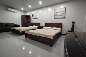 A hotel room with two beds, a sofa, a cabinet, and artwork on the walls. - La Belladoza near NAIA T1 Airport (Paranaque)
