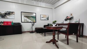 A hotel lobby with a check-in counter, a staircase, and a dining area with a table and chairs. - La Belladoza near NAIA T1 Airport (Paranaque)