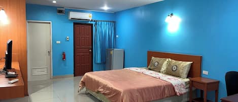 A bedroom with a bed, a desk, a chair, a wardrobe, and an air conditioning unit.