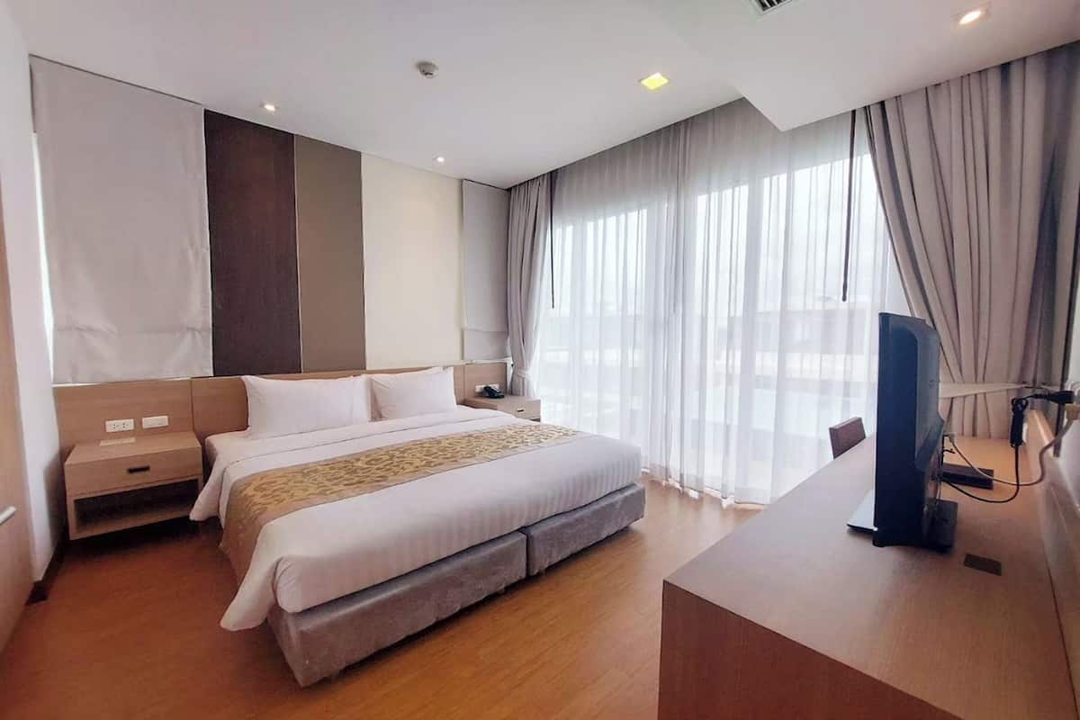 Een hotelkamer met een groot bed, een bureau en een televisie.