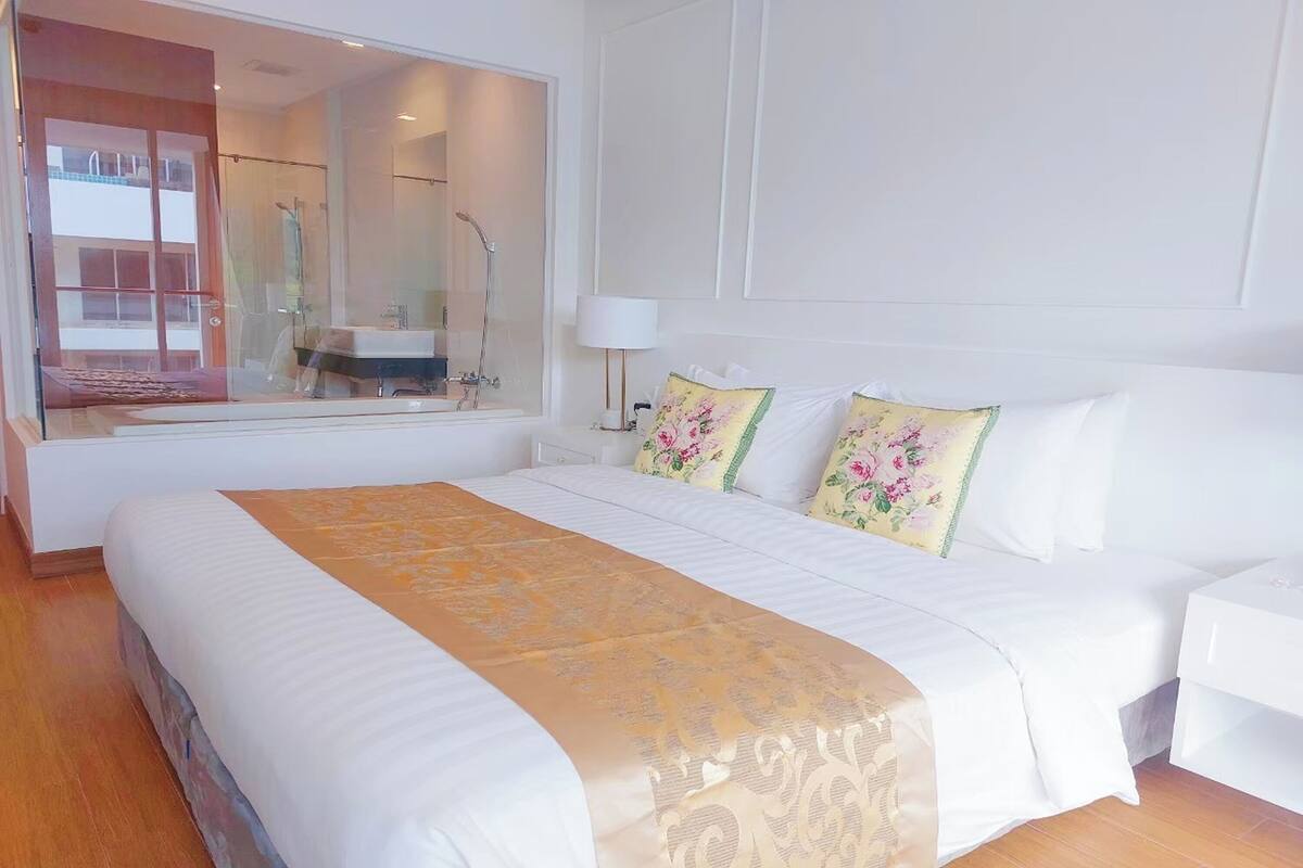 Een hotelkamer met een groot bed, nachtkastje, spiegel en uitzicht.