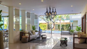 Amplia sala de estar con vista a la piscina, muebles modernos y un candelabro.