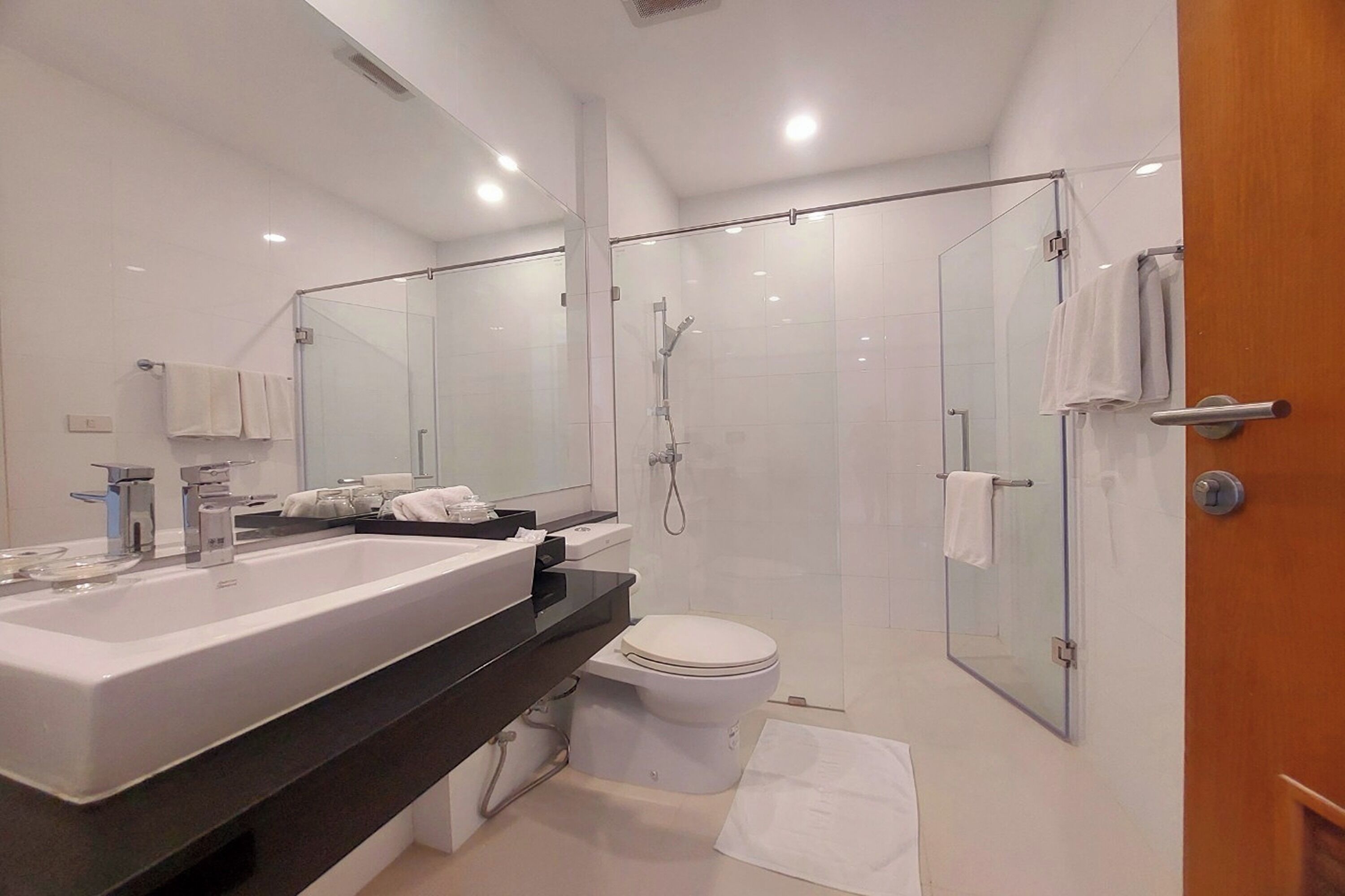 A modern bathroom with a large sink, toilet, and glass-enclosed shower area.