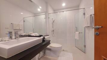 A modern bathroom with a large sink, toilet, and glass-enclosed shower area.