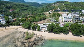 Zona costera con playa, agua cristalina y edificios de diseño moderno.