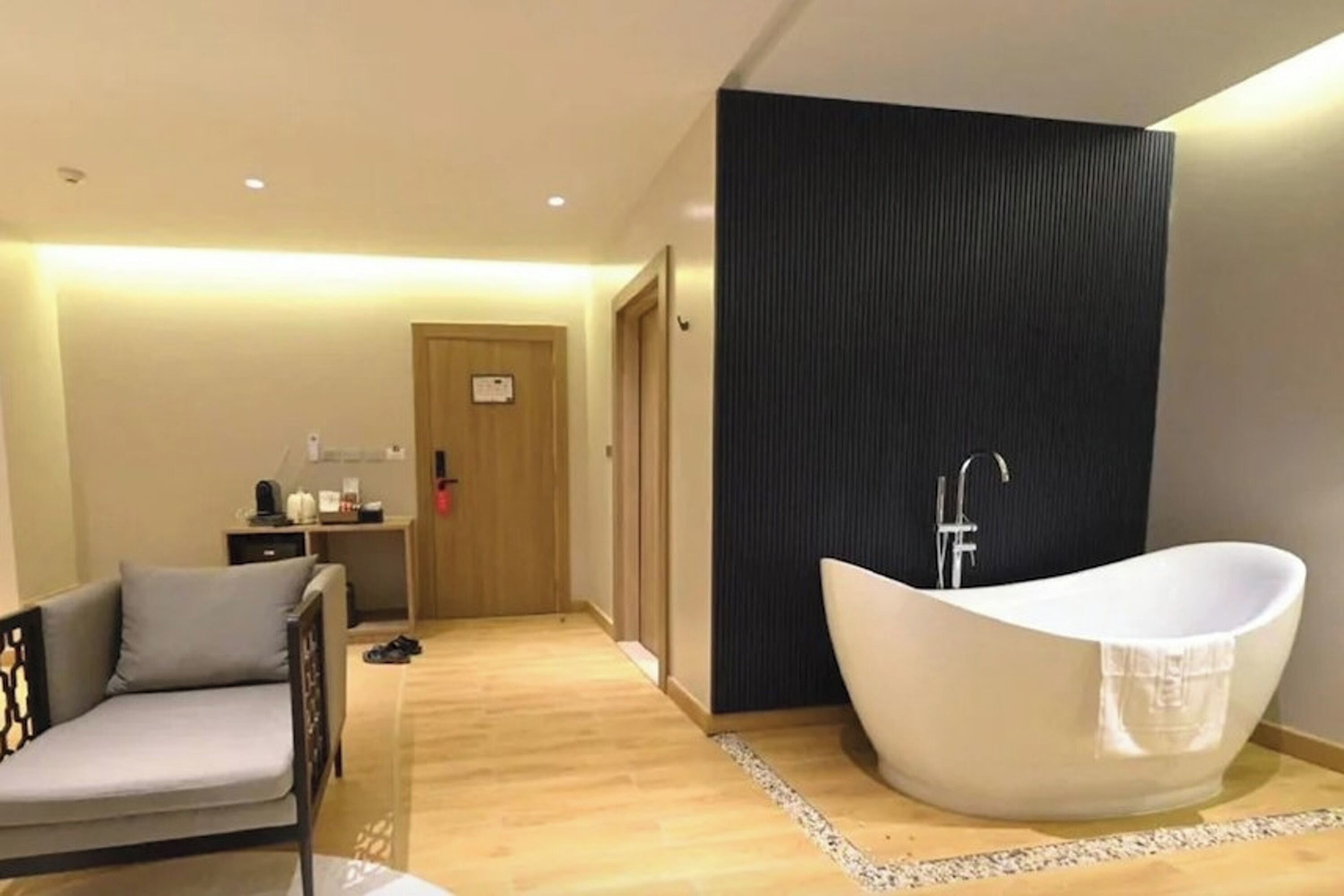 Un baño moderno con bañera independiente, suelo de madera y diseño minimalista.