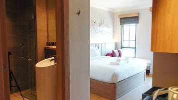 Een moderne hotelkamer met een groot bed, een douchecabine van glas, een nachtkastje en een raam met uitzicht.