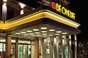 Un hotel con un llamativo letrero 'DE ONE DEF', amplias ventanas y un área de entrada bien iluminada.