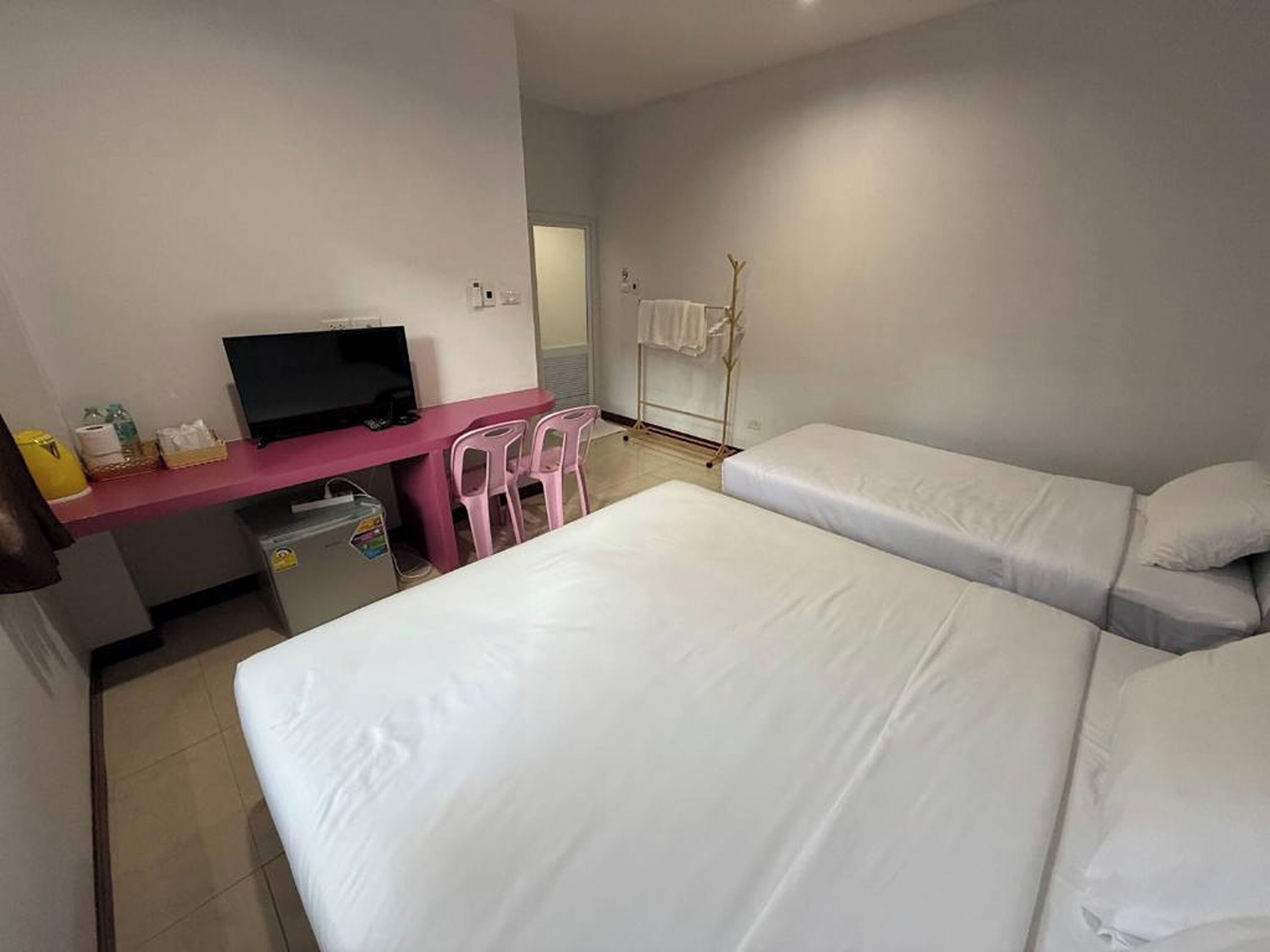 Habitación de hotel con dos camas individuales, un escritorio con televisor y una silla.