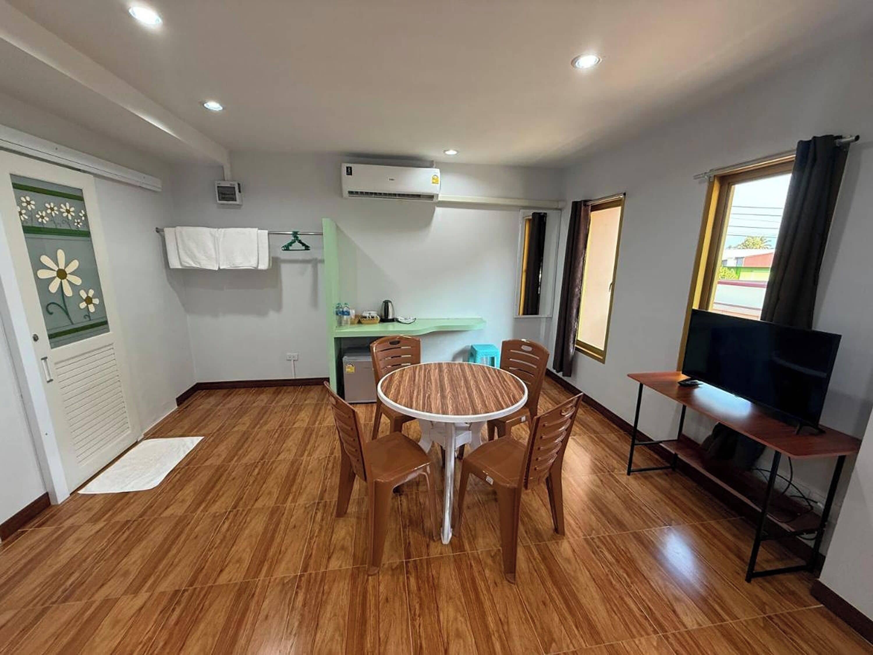 A compact living space with a dining area, kitchenette, and a TV on a stand.