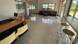 Un salón amplio con sofá, mesa de comedor con sillas y un gran ventanal con vistas al exterior.