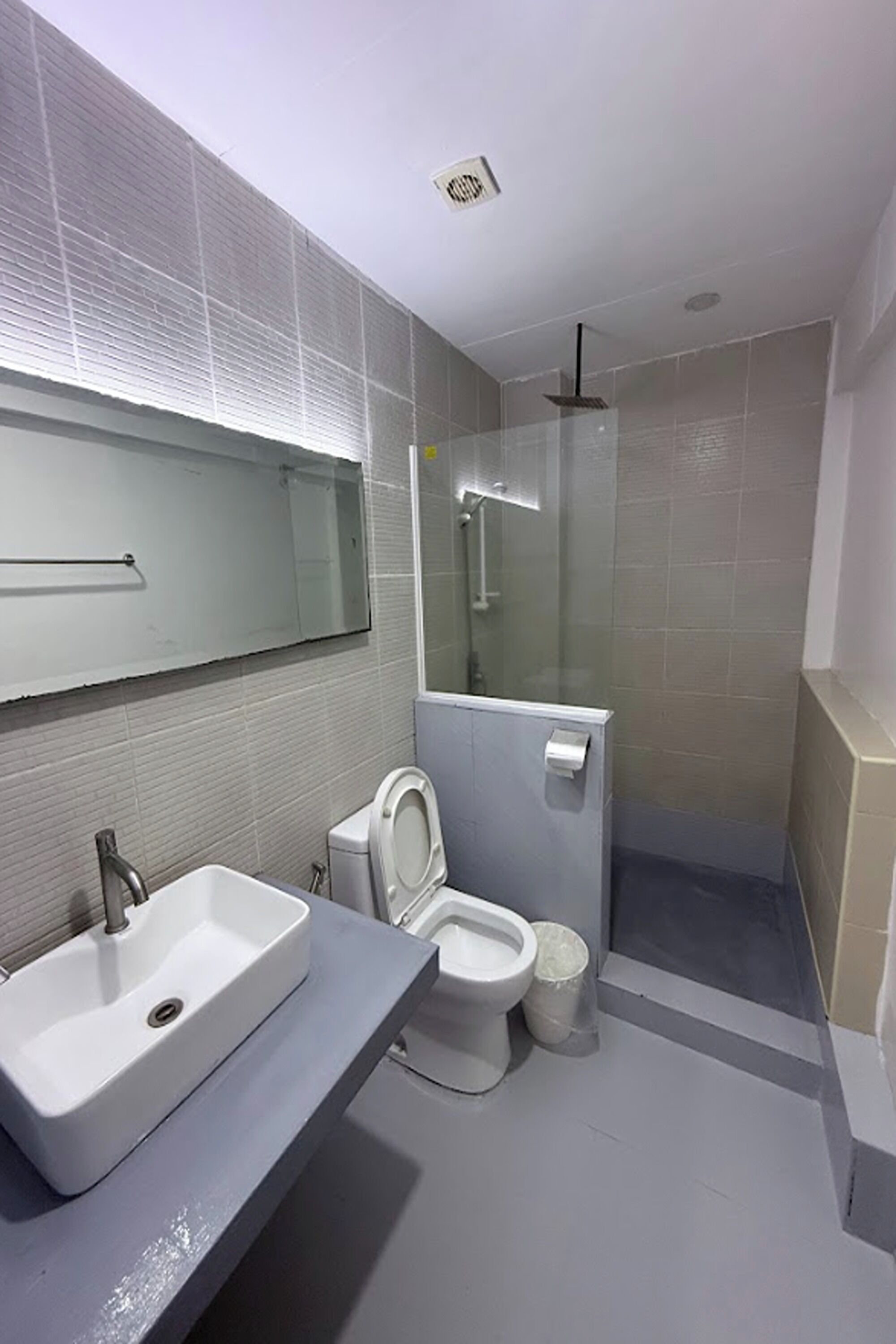 Une salle de bain moderne avec un grand miroir, un lavabo, des toilettes et un espace douche.