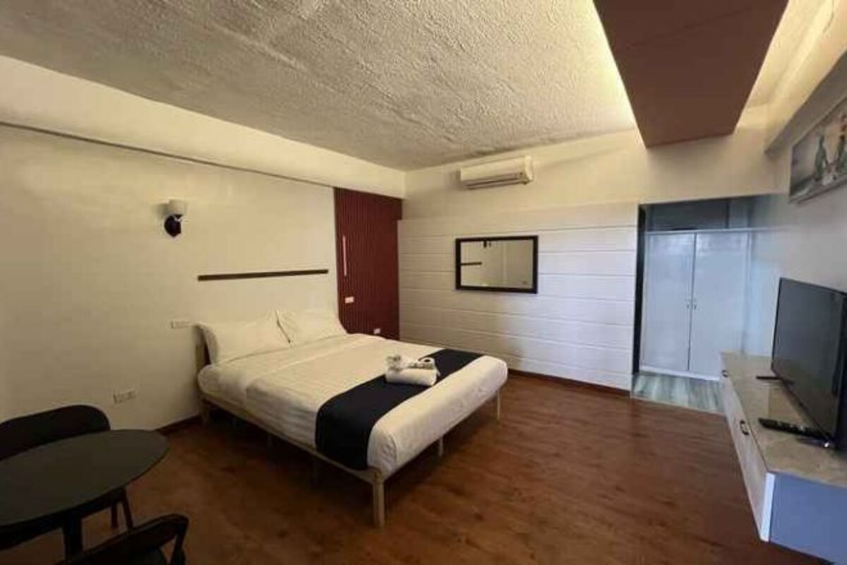 Une chambre d’hôtel équipée d’un lit, d’un bureau, d’une chaise, d’une télévision et d’une armoire.