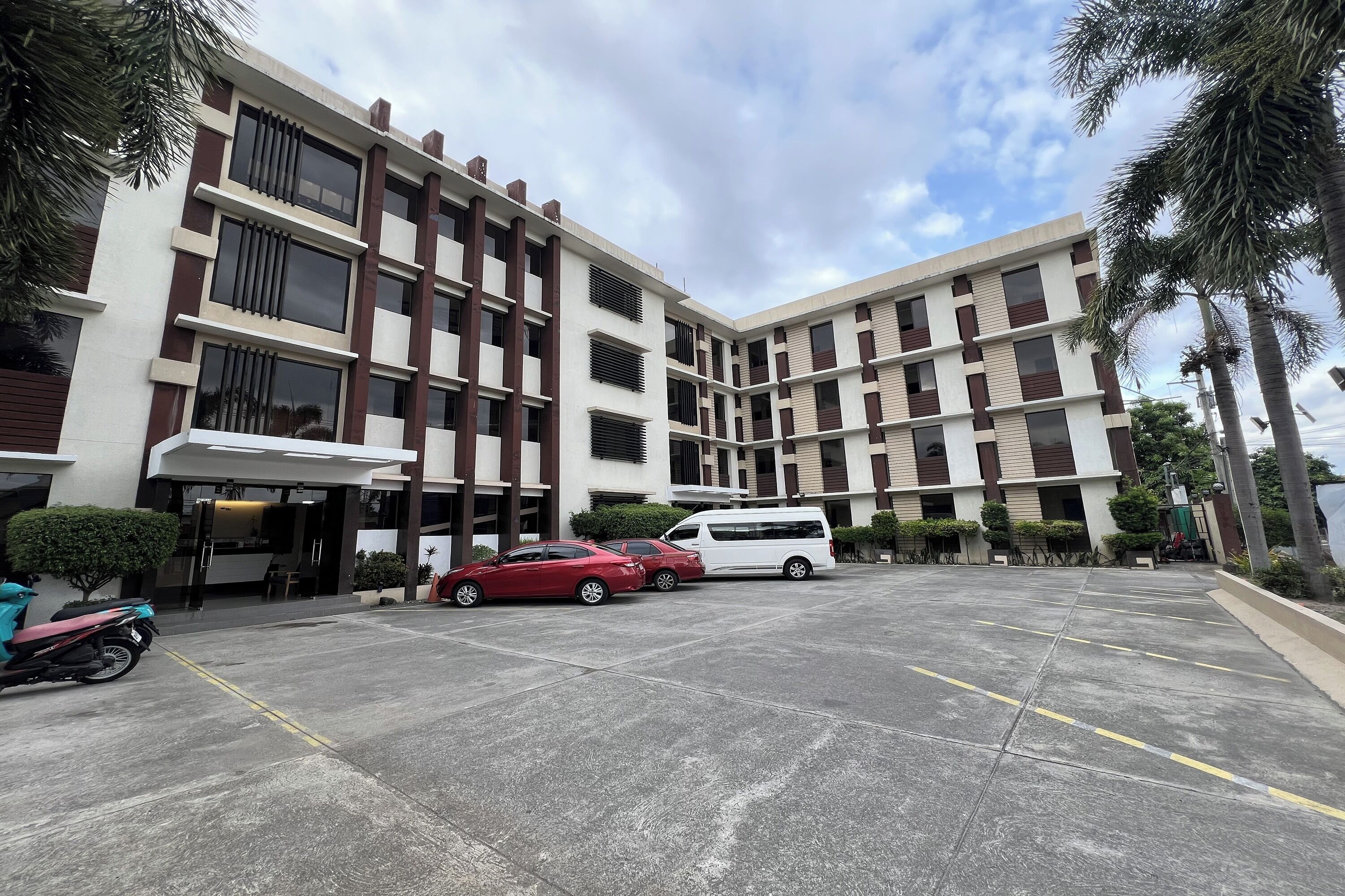 A multi-story building with a parking area in front.